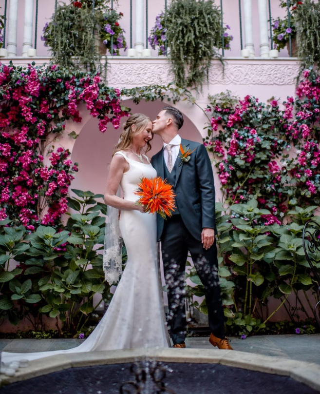Wedding florist for Port Lympne | Image of a bride and groom holding a floral bouquet | orange wedding flowers
