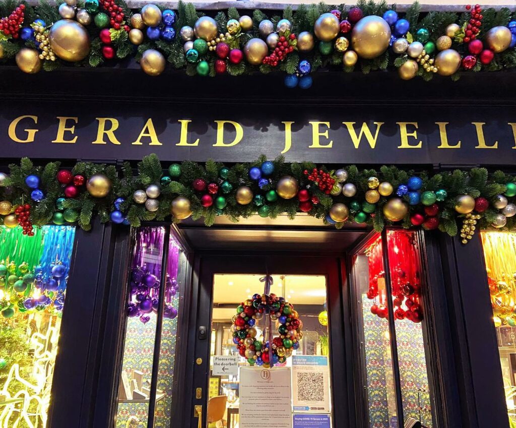 Christmas display Canterbury jeweler storefront- golds, greens and reds in festive bauble display